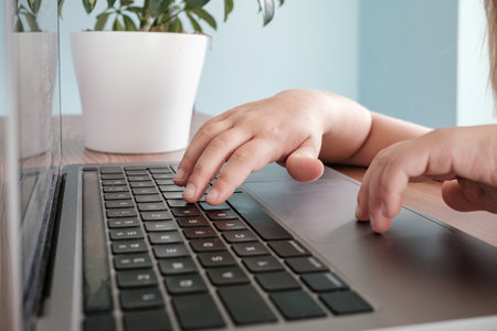 childrens hands typing on laptop keyboard on table