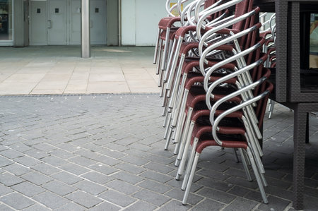 stack of chairs stands near a closed restaurantの写真素材