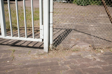 hole in the metal mesh of the chain-link fence, someone tore it open and entered the territoryの写真素材