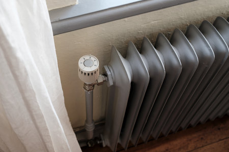 Radiator with a thermostat that reduces the heating temperature. Concept of energy saving, due to the increase in heating costs.の写真素材