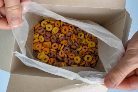 hands open a box of cereal corn ringsの写真素材
