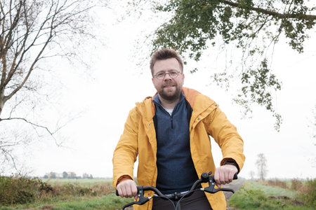 Man in a yellow windbreaker on a bicycle on a foggy morning. Active weekend and healthy lifestyle.の写真素材