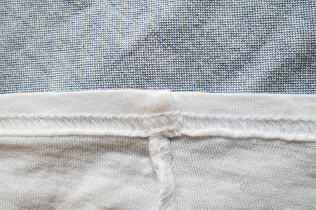 Fabric textured background in gray and white with overlock seams. Copy space. Flatley.