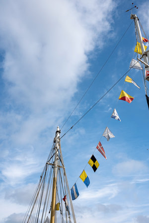 Flags of European countries hang on the mast of the yacht, against the blue sky. Bottom view.の写真素材