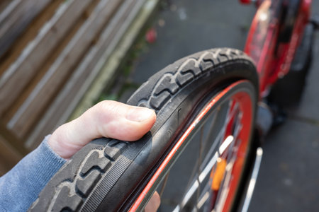 Punctured bicycle wheel. Cyclist presses finger on the tire and checks its deflation. Bike repair.の写真素材