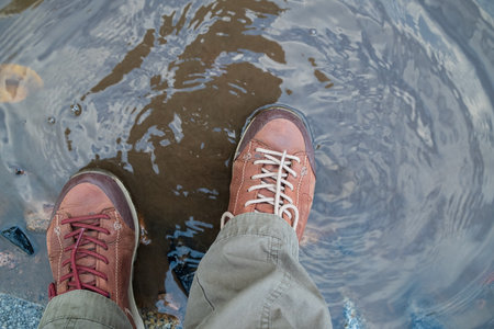 Feet in comfortable trekking shoes suitable for long walks stand in a puddle. Flatley.の写真素材