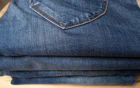 Jeans folded in a pile on a wooden shelf. Concept of the trading industry, sales. Close-up.の写真素材