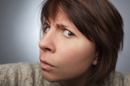 Girl looks suspiciously forward, furrowing forehead. Peep and spy on someoneの写真素材