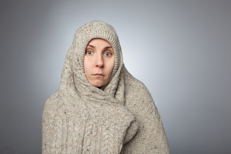 girl hid in a large sweater and surprised and confused looking at the cameraの写真素材