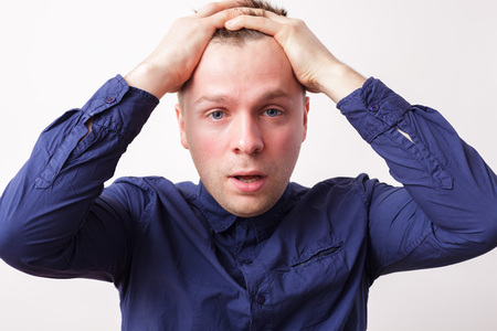 Young man in despair covers his head with Â hands. Worry due to problems and stressの写真素材