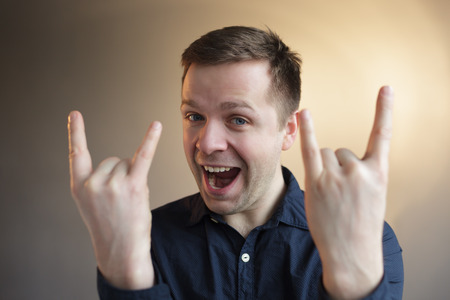 Man shows horns gesture. Fan of heavy metal music