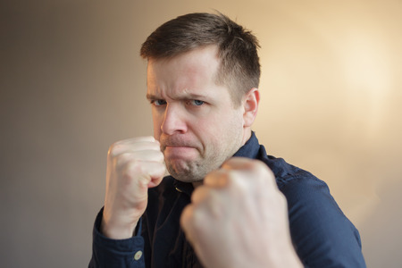 Young man protects himself by clenching his fistsの写真素材