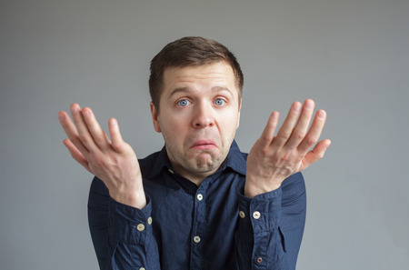 Young man in shirt begging for something, holding out his hands in supplicationの写真素材