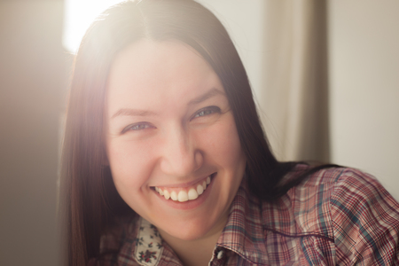 Beautiful girl with long black hair smiles broadly and laughsの写真素材