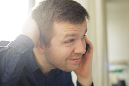 Man talks on phone and with doubt holds his headの写真素材