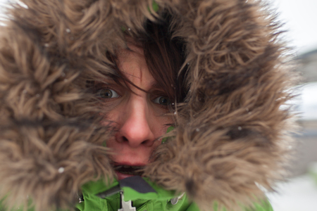 Frozen girl in fur hood in despair is looking forwardの写真素材