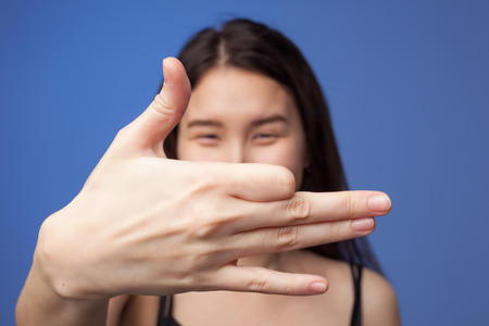 Asian girl shows the dog's face from the fingers. A figure from the theater of shadows.の写真素材