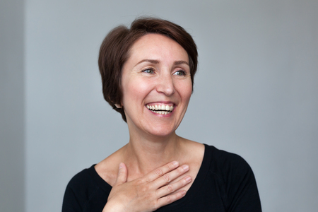 A beautiful middle-aged woman laughs cheerfully. She's in a good mood.の写真素材