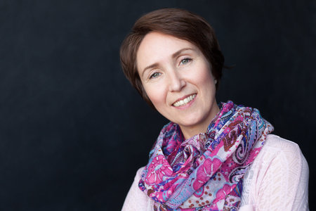 Close up portrait of smiling brunette woman with colorful scarf on black backgroundの写真素材