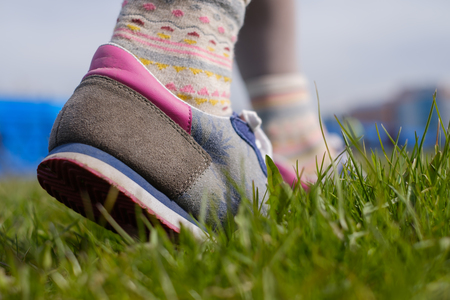 The girl is walking along the green grass in sneakers. Spring walk in the parkの写真素材