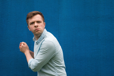 A young greedy man hides something in his hands and looks warily forward.の写真素材