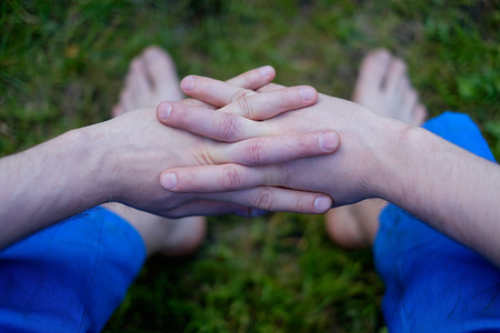 Caucasian man sitting on grass with crossed fingersの写真素材