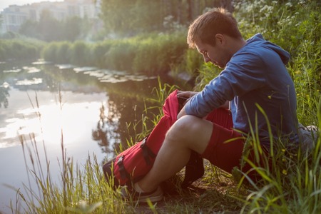 Young man sitting next to river and enjoying in sunny day.の写真素材