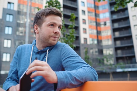 Portrait of mature man in casual clothing using digital tablet outdoors.の写真素材