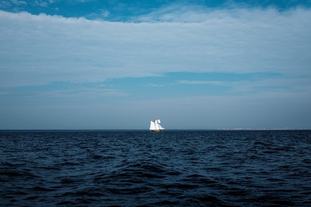 Dramatic seascape with small white yacht far away. Dark sea waterの写真素材