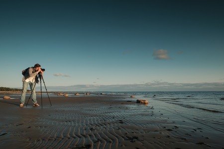 Young caucasian man making photo of landscape on seaside.の写真素材