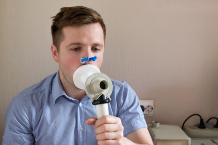 Young man testing breathing function by spirometry