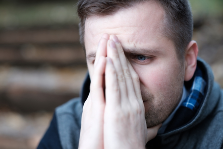 The young man covers his face with his hands. He is about to cry.の写真素材