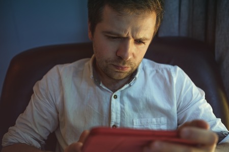 Young caucasian man at laptop computer with light reflection from the screen to the face working at home.の写真素材