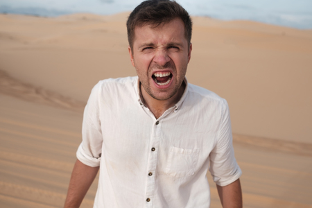 Angry man shouting accusing someone standing in desertの写真素材