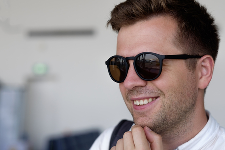 A smiling man in sunglasses looks out the window at the airportの写真素材