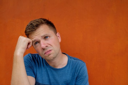 Close up portrait of caucasian disappointed stressed young man on red background. He is about to...