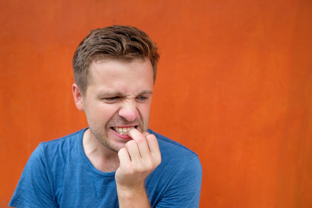 Caucasian mature man on red background gnawing nails.の写真素材