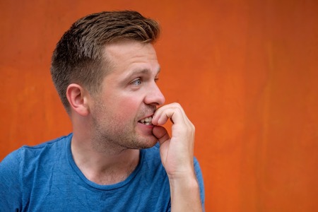 Caucasian mature man on red background gnawing nails.の写真素材