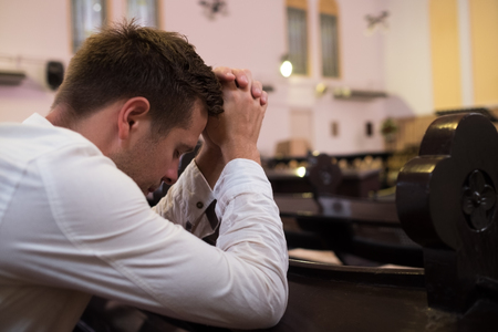 caucasian man praying in church. He has problems and ask God for helpの写真素材