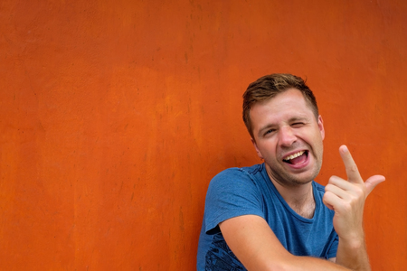 Portrait of an excited casual caucasian man with raised hand and looking at camera on red backgroundの写真素材
