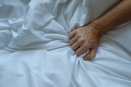 Caucasian man hand grasping on bedの写真素材