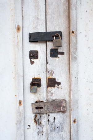 White door with an old lock with traces of previous locks on itの写真素材