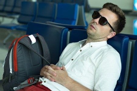 Caucasian man is sleeping in lounge area at the airport.