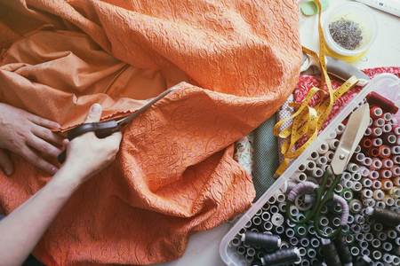caucasian girl cutting orange fabric