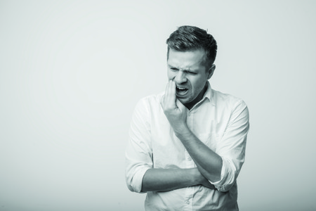 oung caucasian man suffering with a toothache.の写真素材