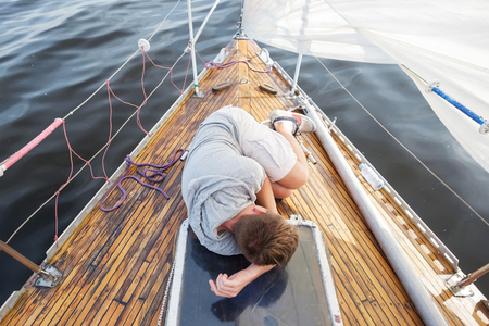 young european man having a nausea seasickness. He is trying to stop vomiting. Travelling on old boat with sailの写真素材