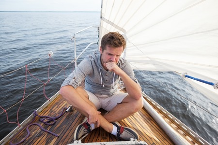 young european man having a nausea seasickness. He is trying to stop vomiting. Travelling on old boat with sailの写真素材