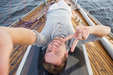 young european man making selphie on yacht. Travelling on old boat with sailの写真素材