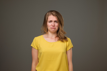 Portrait of discontent european female frowns face in discontent, looks desperately at camera, going to cry standing on black background.の写真素材