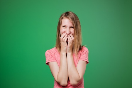 Lovely shy european woman lauging and closing her face with nads. She is shy to hear complimentsの写真素材